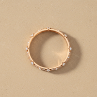 Ultra high-resolution product photo of bangle.
Minimal, premium style on a smooth, flat warm stone background.  
Jewellery lying flat on the surface.  
Clean studio lighting with gentle highlights on metal and gemstones.  
Square format (1:1).  
Single hero piece centred, filling about 65% of the frame with space around it.  
Looks professionally restored and like new.  
No text, no logos, no people.
